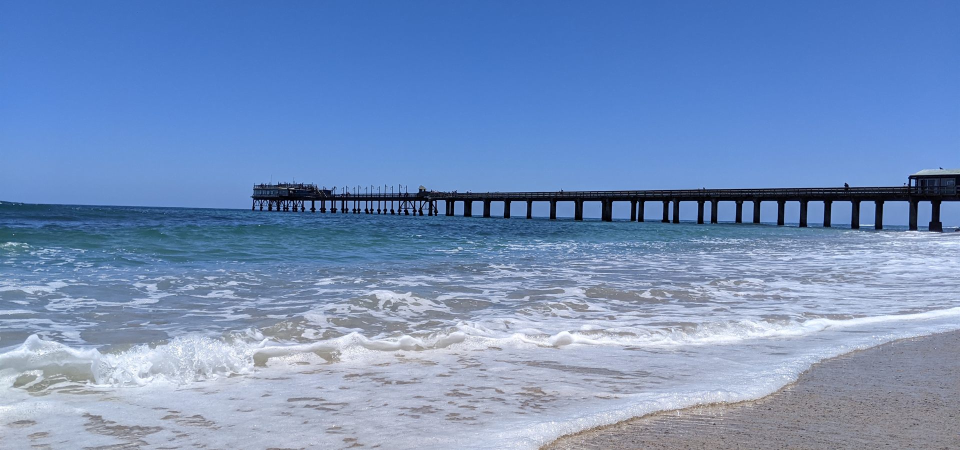 Waves washing onto the beach beside the Swakopmund jetty